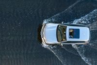 top down shot of a car driving on water with waves running in the air around