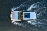 top down shot of a car driving on water with waves running in the air around