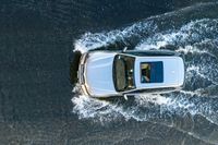 top down shot of a car driving on water with waves running in the air around