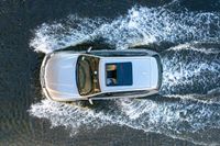 top down shot of a car driving on water with waves running in the air around