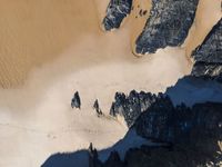 an aerial view of a mountain range covered in snow and rocks with shadows coming from the top of it