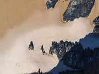 an aerial view of a mountain range covered in snow and rocks with shadows coming from the top of it