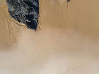 a beach with lots of sand near water and rocks on the side of the beach