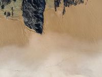 a beach with lots of sand near water and rocks on the side of the beach