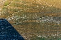 an aerial view of a beach and water and sand with waves on the shore of the ocean