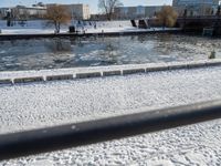 snowy day at the river near the waterfront with a bridge in the background and water flowing below