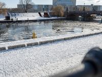 snowy day at the river near the waterfront with a bridge in the background and water flowing below