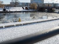 snowy day at the river near the waterfront with a bridge in the background and water flowing below