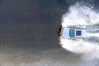 the top view of a small boat is sailing across the water with white spray coming out of the boat