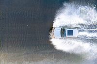 the top view of a small boat is sailing across the water with white spray coming out of the boat