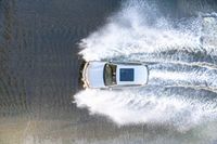 the top view of a small boat is sailing across the water with white spray coming out of the boat