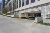 a sidewalk with an entrance to a car park and a building that has graffiti all over the side