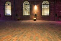 a large brick floor with windows and lamps on top of it lit up at night