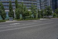 a road and some tall buildings on either side of it and one has trees growing in the grass on the side