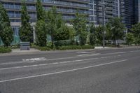 a road and some tall buildings on either side of it and one has trees growing in the grass on the side