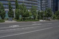a road and some tall buildings on either side of it and one has trees growing in the grass on the side