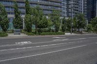 a road and some tall buildings on either side of it and one has trees growing in the grass on the side