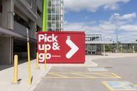 red and white sign for pick up and go parked in a parking lot next to a building