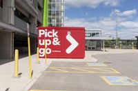 red and white sign for pick up and go parked in a parking lot next to a building