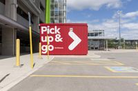 red and white sign for pick up and go parked in a parking lot next to a building