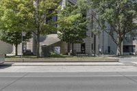 an empty street with the curb painted white in front of a tall building and some trees