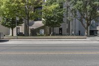 an empty street with the curb painted white in front of a tall building and some trees