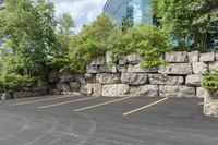 this is an empty parking lot in an empty city park area with a rock wall