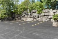 this is an empty parking lot in an empty city park area with a rock wall