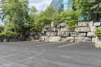 this is an empty parking lot in an empty city park area with a rock wall