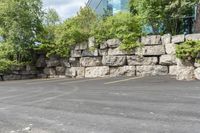 this is an empty parking lot in an empty city park area with a rock wall