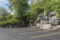 this is an empty parking lot in an empty city park area with a rock wall