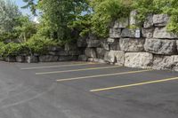 this is an empty parking lot in an empty city park area with a rock wall