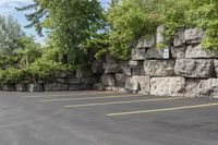 this is an empty parking lot in an empty city park area with a rock wall