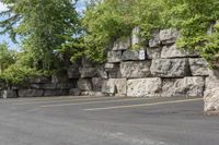 this is an empty parking lot in an empty city park area with a rock wall