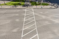 white markings on a sidewalk next to a street sign with a pedestrian crossing in the background