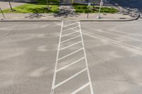 white markings on a sidewalk next to a street sign with a pedestrian crossing in the background