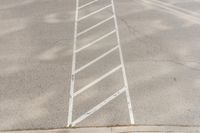 white markings on a sidewalk next to a street sign with a pedestrian crossing in the background