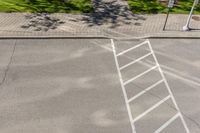 white markings on a sidewalk next to a street sign with a pedestrian crossing in the background