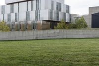 a cement block wall on a grass area outside of the building with a fire hydrant sitting behind it