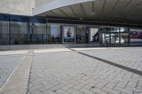 a person sitting at the bench in front of a mall that is empty of people