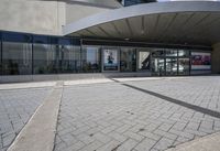 a person sitting at the bench in front of a mall that is empty of people