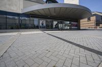 a person sitting at the bench in front of a mall that is empty of people