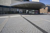 a person sitting at the bench in front of a mall that is empty of people