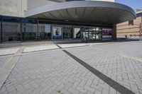 a person sitting at the bench in front of a mall that is empty of people