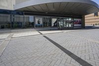 a person sitting at the bench in front of a mall that is empty of people