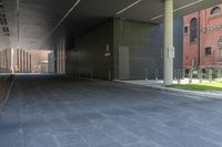 this walkway has a walkway that is surrounded by tall buildings and trees it leads to an atrium