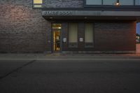 the street side entrance to a brick building is illuminated by an led sign and parking meter