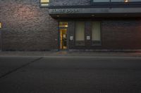 the street side entrance to a brick building is illuminated by an led sign and parking meter