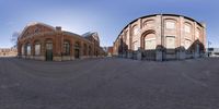 a view of two circular buildings from a nearby angle the building is a red brick and green door