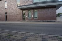 a street in front of a brick building and signs on the building's side